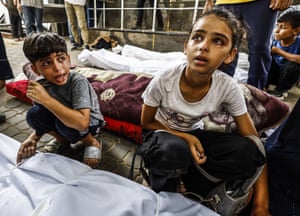 Children sit by the bodies of relatives