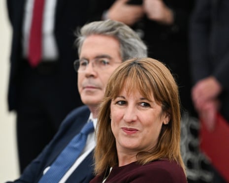 Reeves sitting next to Bessent and smiling at something off camera