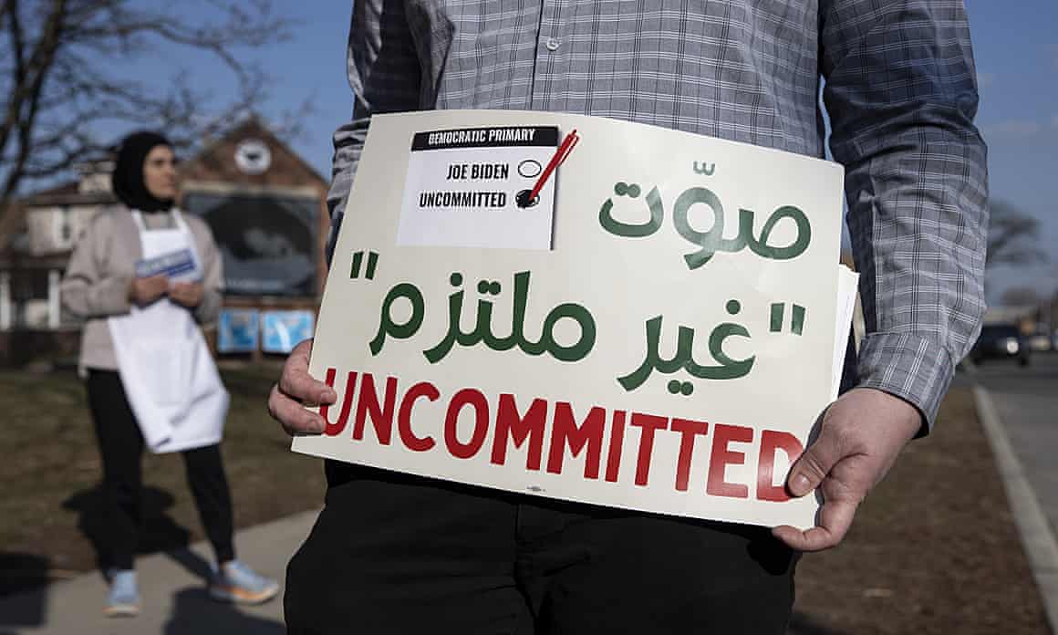 A volunteer holds a sign with green Arabic characters written above a red 'uncommitted'