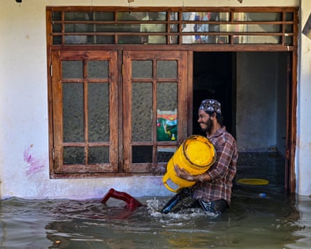 A man carries a gas tank outside his flooded house