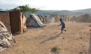 A boy plays with a discarded tyre at a borderland encampment outside the south-east Haitian town of Anse-à-Pitres.