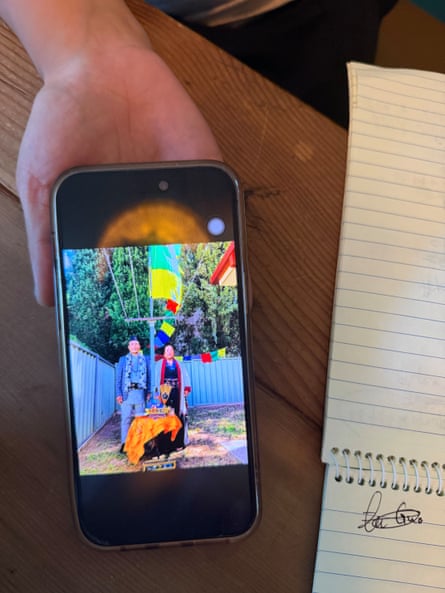 A phone displays a picture of two older people in traditional Nepali clothing.