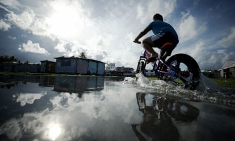 A boy rides through floodwaters near high tide in a  low-lying area of Tuvalu