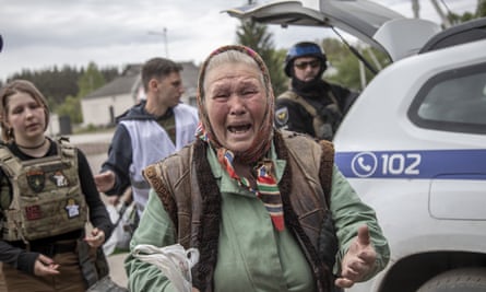 An elderly woman cries and gestures with her hands.