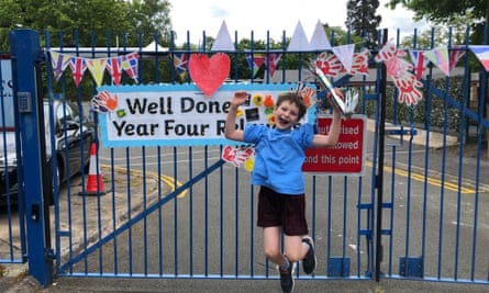 Child jumping with baton in front of school gates decorated with bunting
