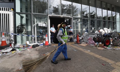 Police officers stand guard as cleaners clear remaining items around the Legislative Council Building after protesters stormed the building in Hong Kong