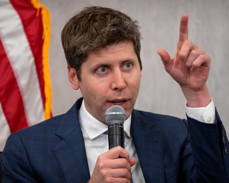 A man gestures while speaking into a mic in front of a US flag.