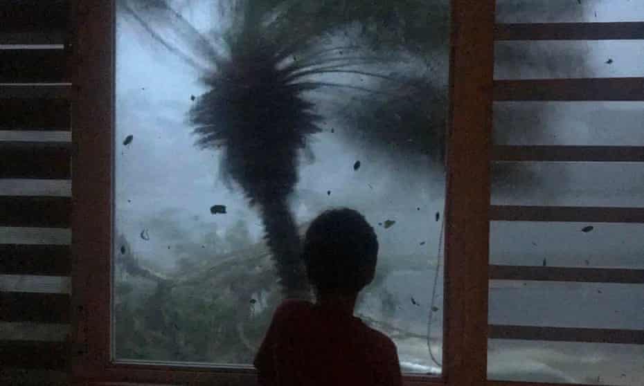 A boy watches the strong winds and rain from Hurricane Maria in September 2017. 