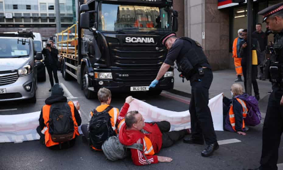 A police officer speaks to Insulate Britain protesters blocking a road near Southwark Bridge