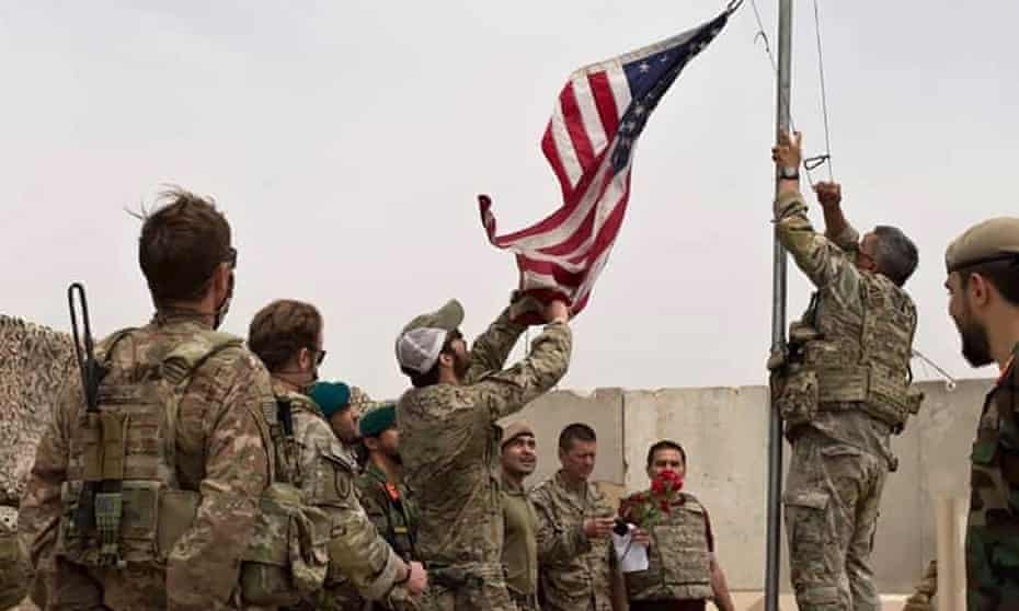 A US flag is lowered as American and Afghan soldiers attend a handover ceremony in Helmand on 2 May 2021.