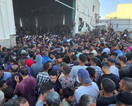 Crowd of people, mostly men and boys, waiting for food