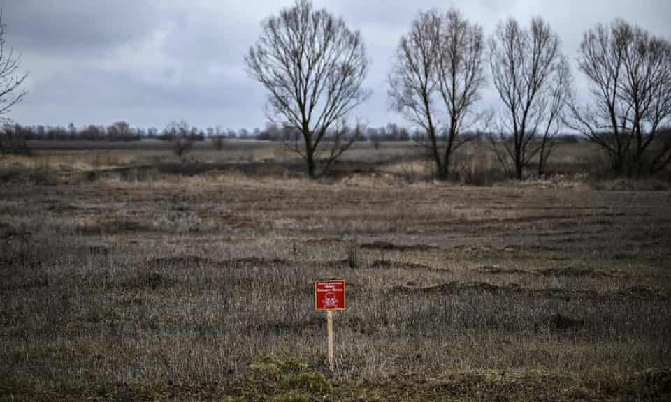 A sign reading ‘Danger: mines’ on a field at the entrance of Nizhyn, north-east of Kyiv, once used to grow crops. Photograph: Aris Messinis/AFP/Getty Images