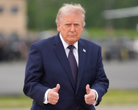 Donald Trump gives two thumbs up to the media while wearing a blue suit