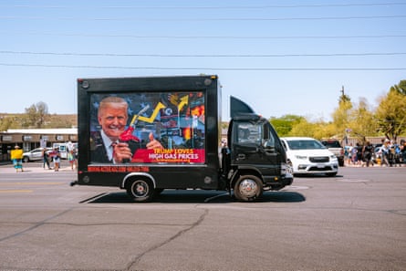 A truck bearing a âÂÂTrump loves high gas pricesâ sign drives past protesters outside an event