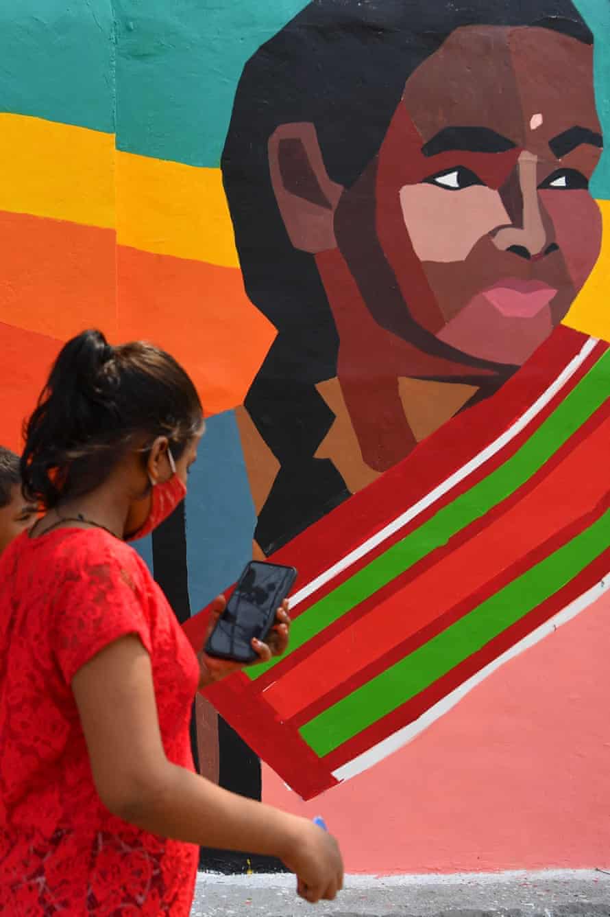 Children walk past a mural painted by members of the Aravani community in Mumbai.