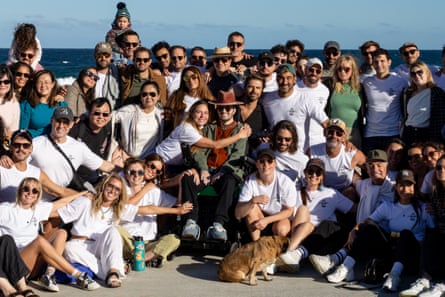 Marc Girod pictured in the centre of a large group of people who are gathered around him on a beach, all looking at the camera