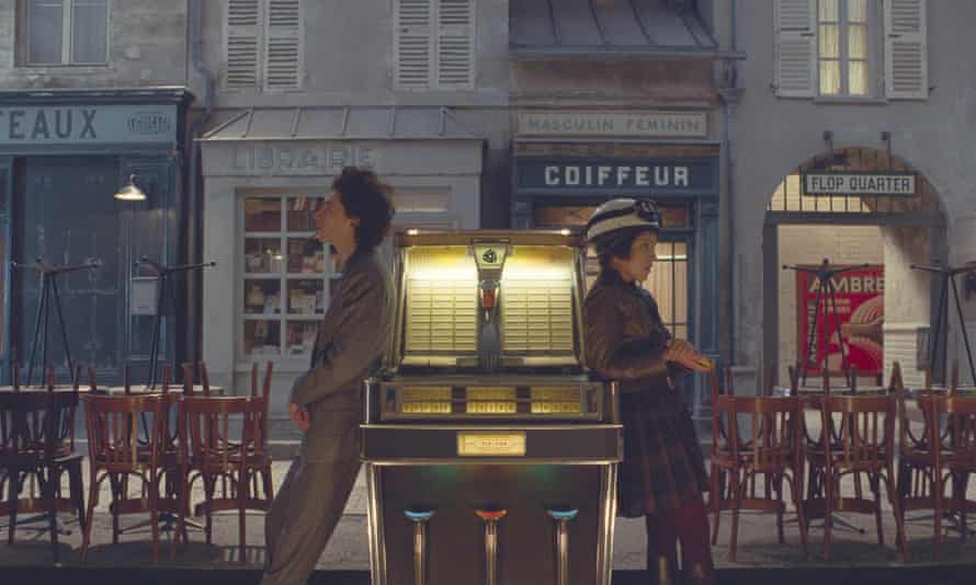 Chalamet and Khoudri leaning on a juke-box, facing in opposite directions on a French street