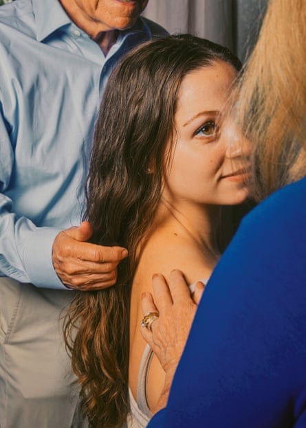 A hazel-eyed, brown-haired woman gazes up at her mother as her dad touches her hair