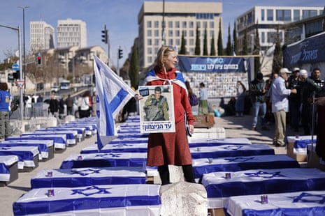 A demonstrator stands amid mock coffins draped in Israeli flags to protest the ceasefire with Hamas outside the Supreme Court in Jerusalem on 16 January.