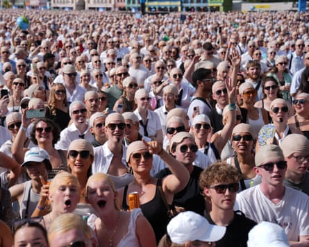 A crowd of men wearing bald caps in an open-air concert