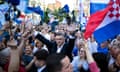 Andrej Plenković waves as he walks through a large crowd of people waving flags and blue flowers
