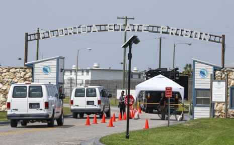Vans transporting execution witnesses wait at a checkpoint beneath the Florida state prison entrance sign