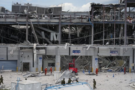 Emergency workers stand near a heavily damaged shopping centre.