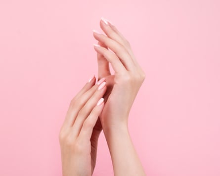 Tender hands with perfect pink manicure on trendy pastel pink background.