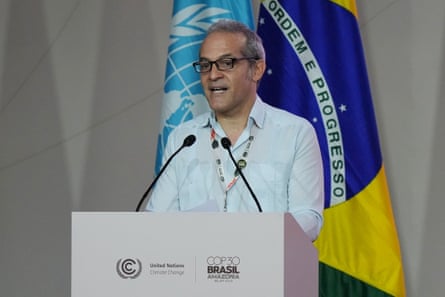 Man wearing black glasses and a white shirt talks at a Cop lectern