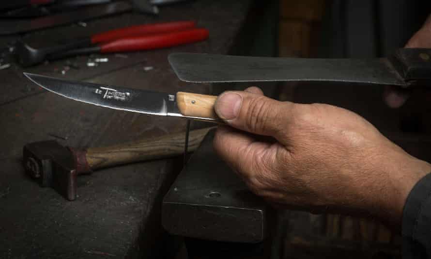 homme tenant un couteau à manche en bois