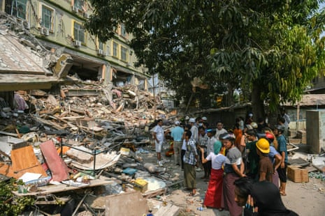 People look on as teams of rescue workers attempt to free residents trapped under the rubble of the destroyed Sky Villa condominium development in Mandalay on Saturday.