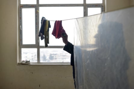 A woman who is obscured by a panel of material hangs up washing inside a room