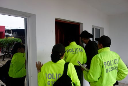 Police in hi-vis jackets stand outside the door of a house as they conduct a raid against wildlife crime in Colombia.