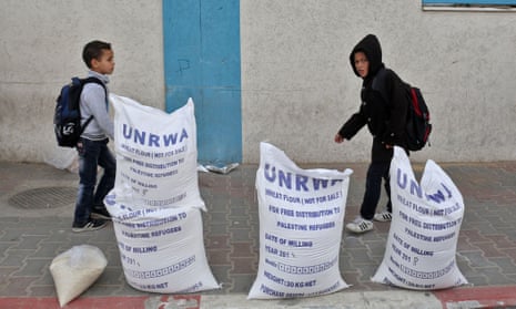Palestinian schoolboys walk past flour outside an aid distribution centre run by the United Nations Relief and Works Agency (UNRWA) in Rafah in the southern Gaza Strip.