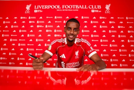 Alexander Isak holds a pen while signing for Liverpool.