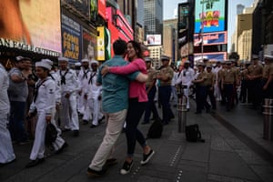 New York, US. Service personnel walk past a couple dancing in Times Square, as part of Fleet Week celebrations, a week-long tribute to sea services