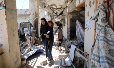 A Palestinian woman stands in a heavily damaged building
