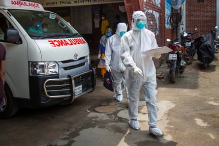 Masked health workers in white protective suits in the street