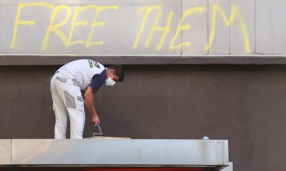 Writing on Park Hotel that says 'Free them' following a pro-refugee protest. A worker is about to paint over it