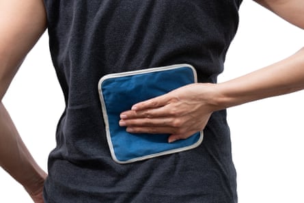 A woman putting an ice pack on her painful back