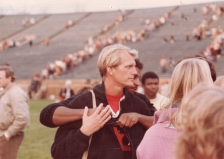 A man in a sports stadium being hugged from behind by another man