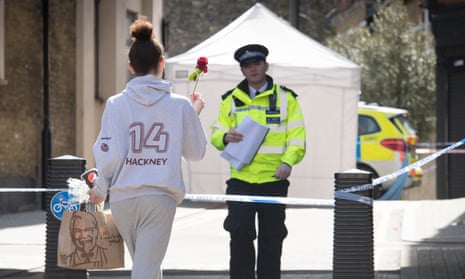 A woman brings a flower to the scene in Hackney in east London where a man died after being stabbed.