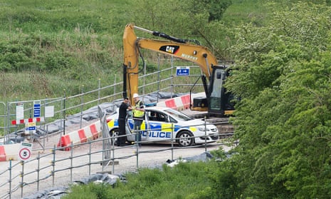 A digger with a police car next to it at a construction site