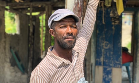 Jean Joseph, a vetiver farmer, stands in front of his destroyed home in southern Haiti