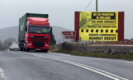 Traffic crossing the border into Northern Ireland from the Irish Republic next to a poster protesting against a hard brexit near Dundalk.