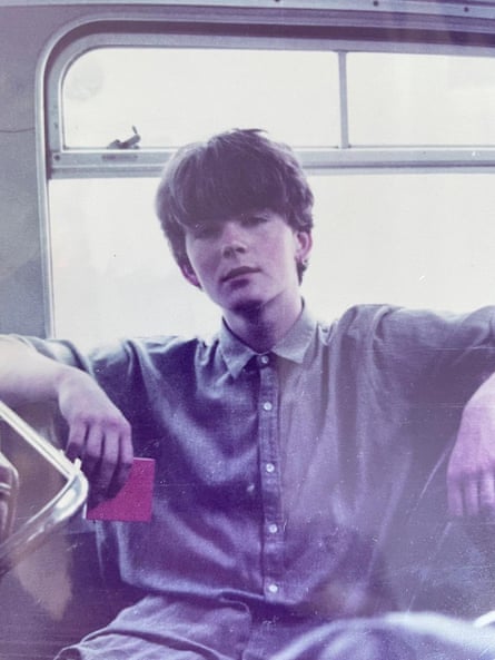 A faded photo of an 18-year-old man with blue buttoned up shirt and dark hair sat on a bus