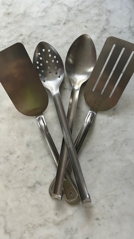Overhead shot of two large metal spoons and two egg flippers on a marble surface.