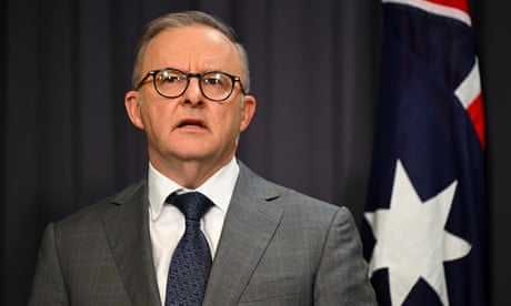 Anthony Albanese speaks at a press conference with an Australian flag behind him
