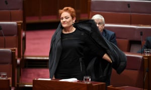 One Nation leader Pauline Hanson pulls off an Islamic veil she wore into the Senate chamber.