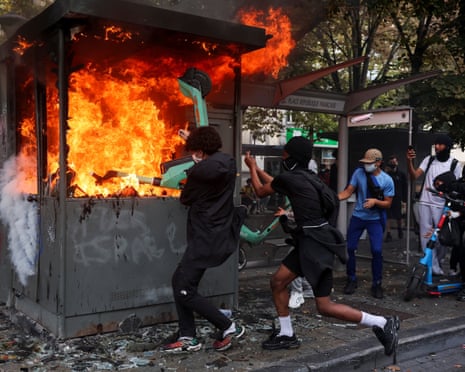 People attempt to put an electric scooter into a burning structure on a street in Liège, Belgium.